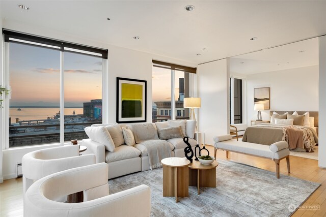 living room with a water view, a baseboard heating unit, and light wood-type flooring