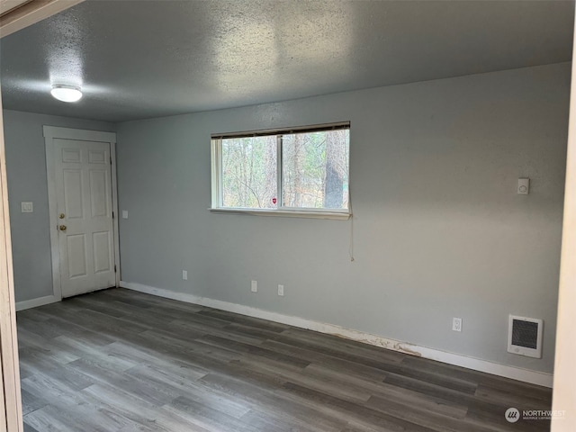 spare room with a textured ceiling and hardwood / wood-style floors