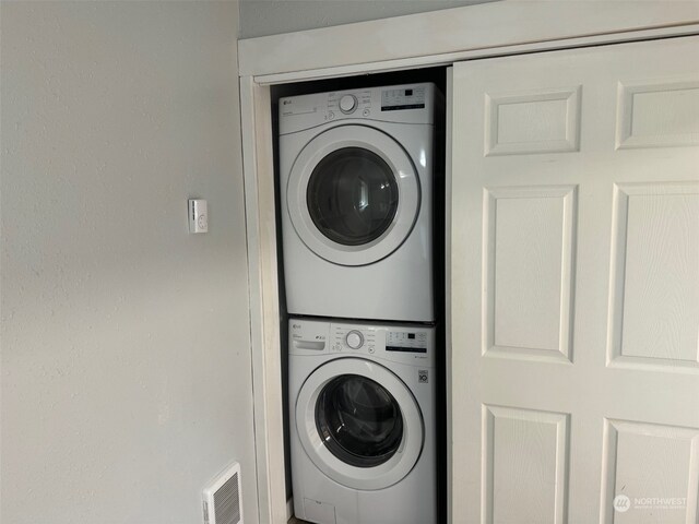 washroom featuring stacked washer / drying machine