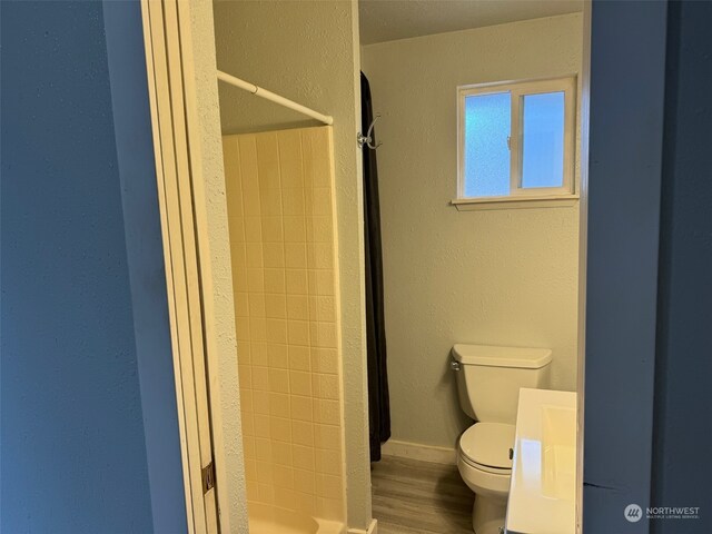 bathroom featuring hardwood / wood-style flooring, walk in shower, and toilet