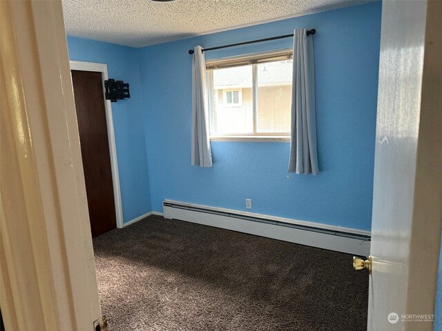 carpeted spare room featuring a textured ceiling and a baseboard heating unit