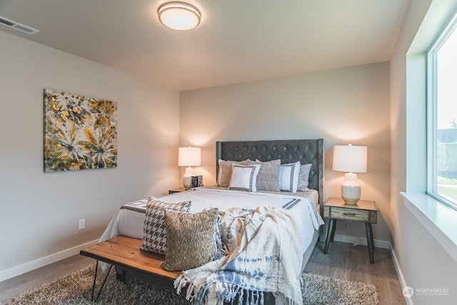 bedroom featuring multiple windows and dark hardwood / wood-style flooring