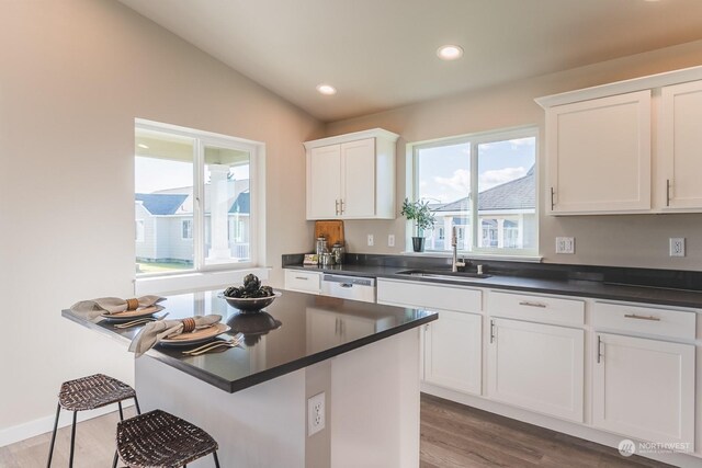 kitchen featuring hardwood / wood-style floors, a breakfast bar, sink, vaulted ceiling, and white cabinetry