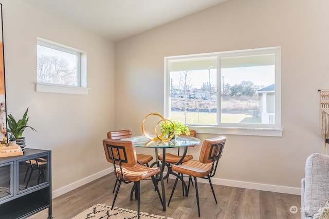 dining area featuring lofted ceiling, hardwood / wood-style flooring, and a healthy amount of sunlight