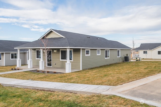 ranch-style house with central AC unit, covered porch, and a front lawn