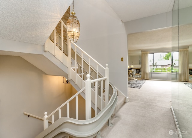 stairway featuring carpet, a notable chandelier, and a textured ceiling