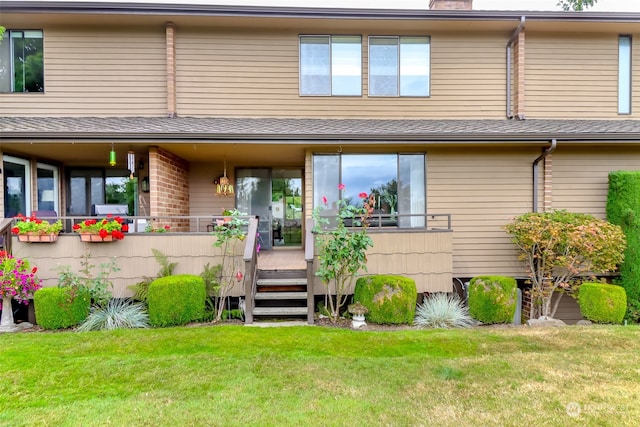 rear view of house featuring a lawn and a deck