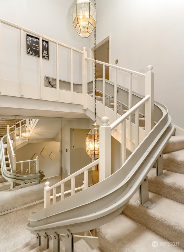 staircase featuring carpet floors, a high ceiling, and a notable chandelier