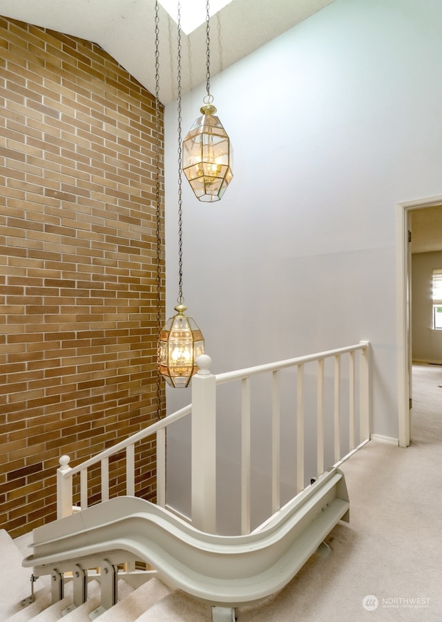 bathroom with brick wall, high vaulted ceiling, and an inviting chandelier