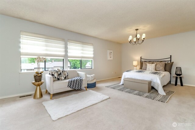 bedroom with a textured ceiling, a chandelier, and light carpet