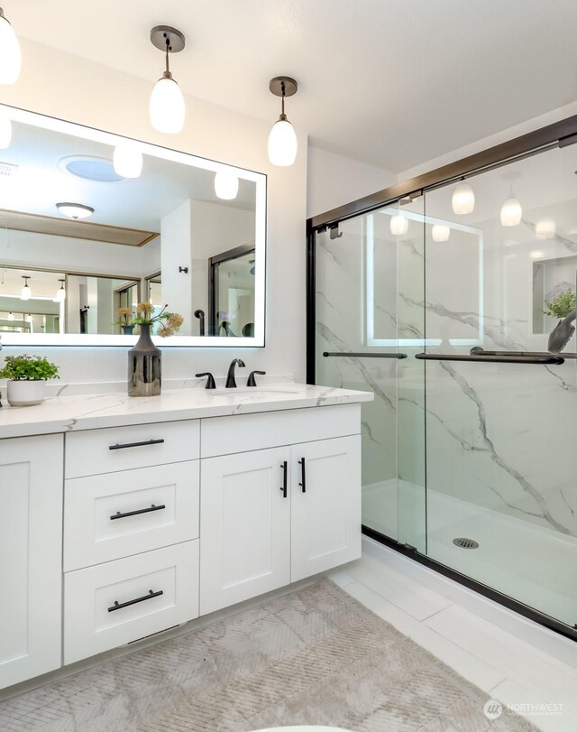 bathroom featuring tile patterned floors, a shower with door, and vanity