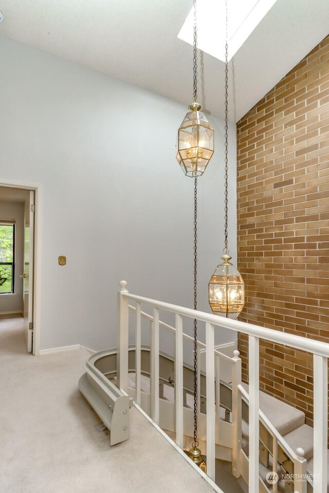 interior space featuring carpet flooring, brick wall, and lofted ceiling