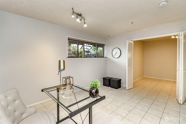 sitting room featuring light tile patterned flooring, rail lighting, and a textured ceiling