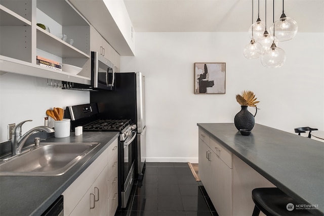 kitchen with a breakfast bar, sink, decorative light fixtures, appliances with stainless steel finishes, and dark tile patterned flooring