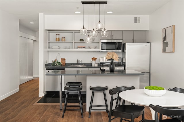 kitchen featuring sink, hanging light fixtures, dark hardwood / wood-style floors, a breakfast bar area, and stainless steel appliances