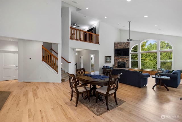 dining space featuring a ceiling fan, light wood-style floors, a fireplace, and stairs