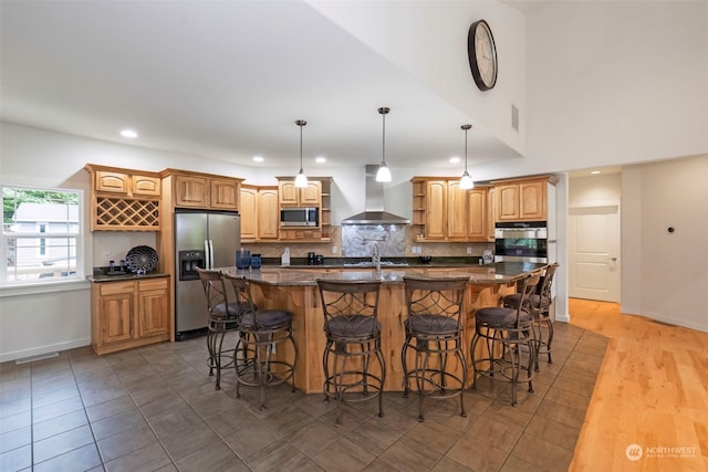 kitchen with a large island, tasteful backsplash, visible vents, appliances with stainless steel finishes, and wall chimney range hood