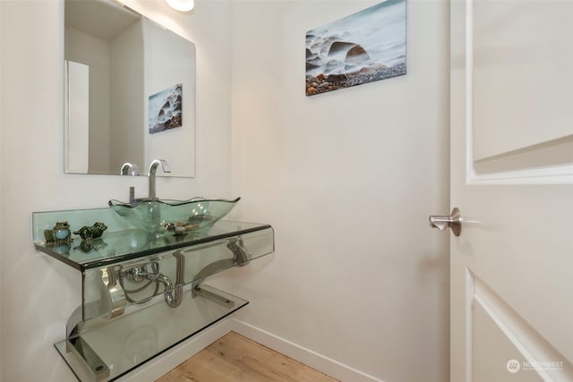 bathroom with a sink, baseboards, and wood finished floors