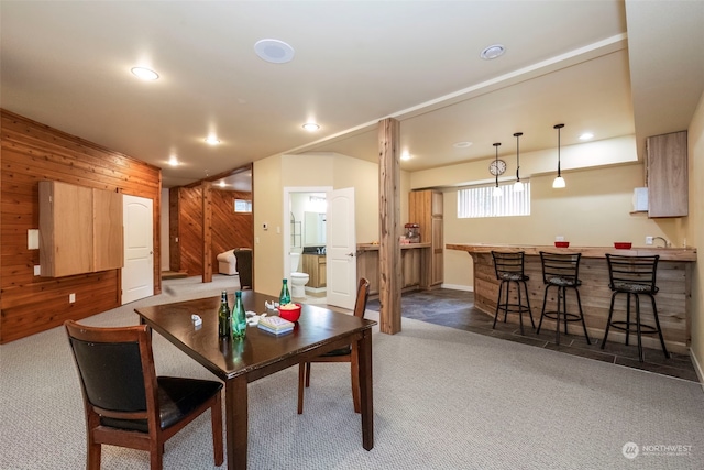 carpeted dining room featuring bar, wooden walls, and recessed lighting