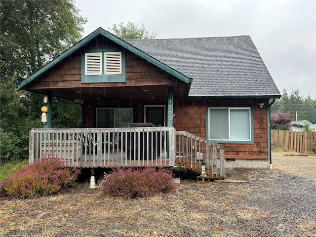 chalet / cabin featuring a shingled roof and fence