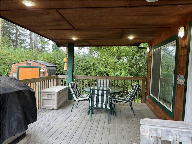 deck featuring a shed, outdoor dining area, an outdoor structure, and area for grilling