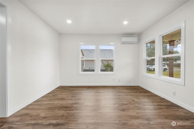 spare room with an AC wall unit and dark hardwood / wood-style floors