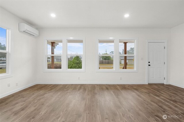 interior space featuring hardwood / wood-style flooring, a wall mounted air conditioner, and a wealth of natural light