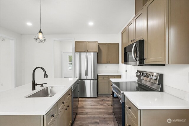 kitchen with a kitchen island with sink, sink, hanging light fixtures, stainless steel appliances, and dark hardwood / wood-style flooring