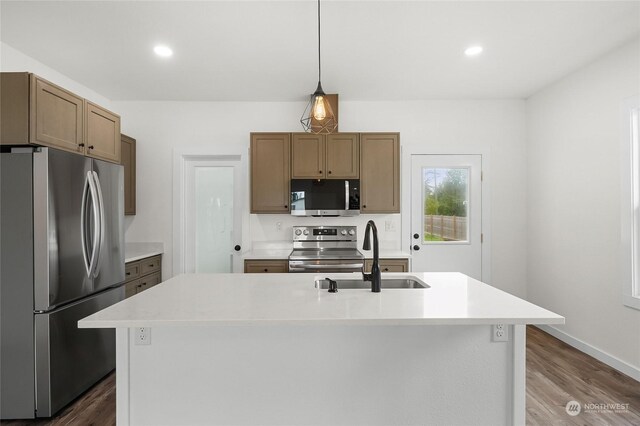 kitchen with a center island with sink, stainless steel appliances, hanging light fixtures, and dark wood-type flooring