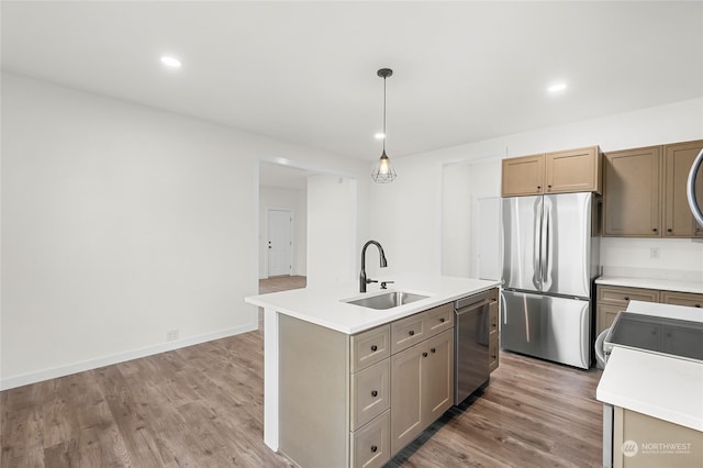 kitchen with pendant lighting, hardwood / wood-style flooring, sink, an island with sink, and stainless steel appliances