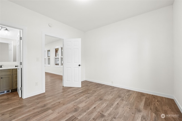 unfurnished bedroom with connected bathroom and light hardwood / wood-style floors