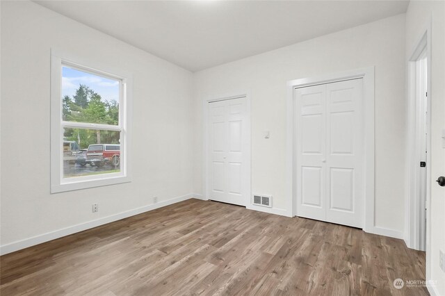 unfurnished bedroom featuring two closets and light hardwood / wood-style flooring