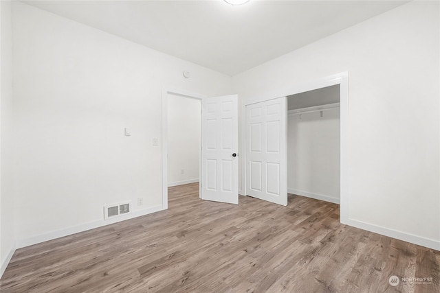 unfurnished bedroom with light wood-type flooring and a closet