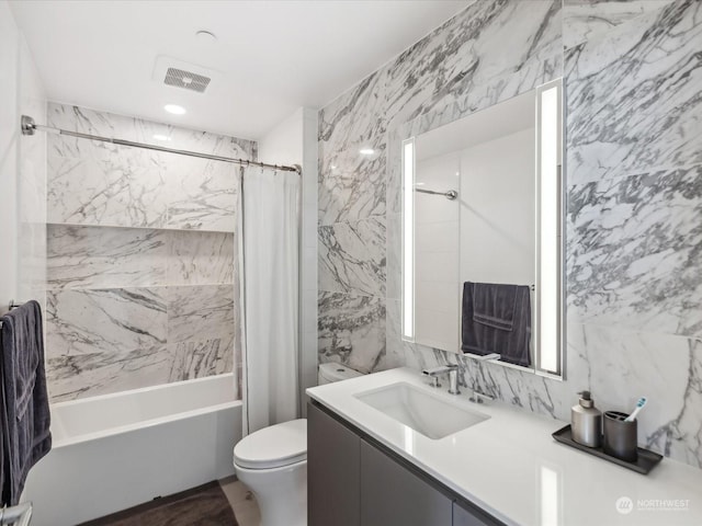 full bathroom featuring vanity, visible vents, shower / tub combo, tile walls, and toilet