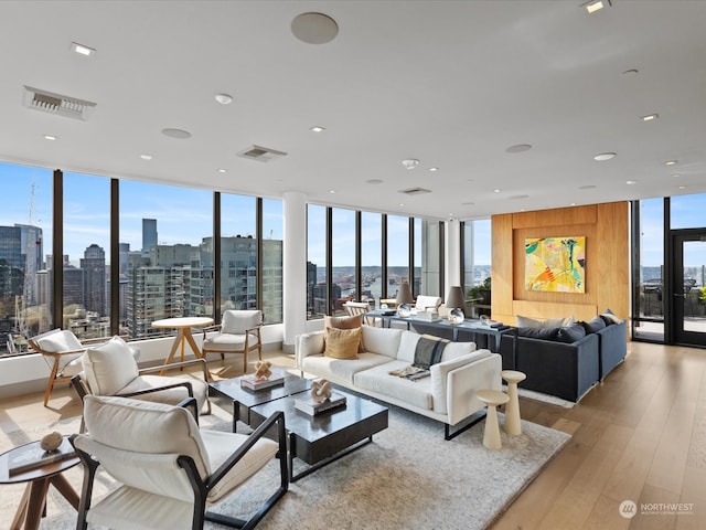 living room with plenty of natural light, light hardwood / wood-style floors, and a wall of windows