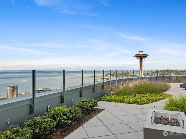 view of community featuring a fire pit, a water view, and fence