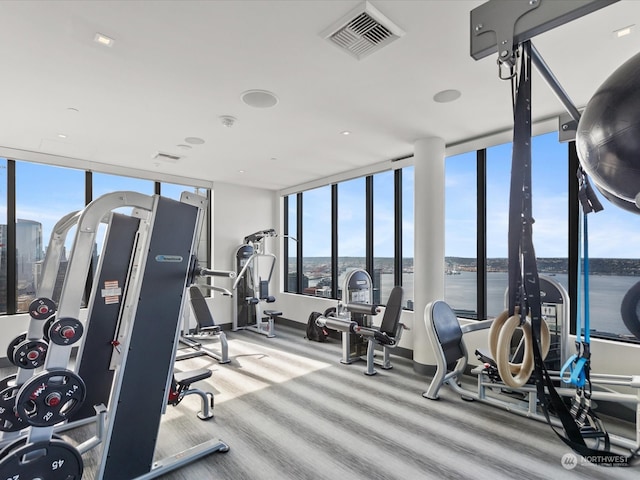 exercise room featuring a wall of windows and a water view