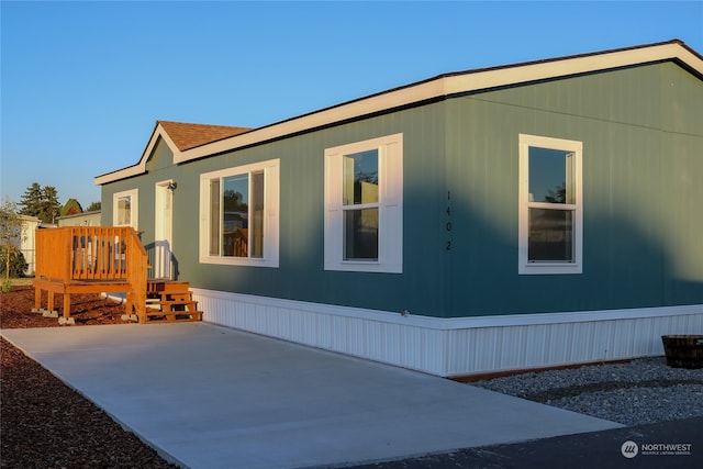 view of property exterior featuring a wooden deck and a patio area