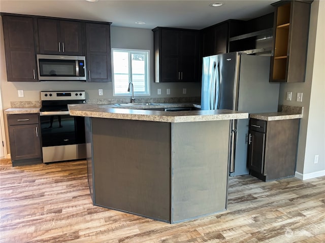 kitchen with stainless steel appliances, sink, dark brown cabinets, and light hardwood / wood-style floors