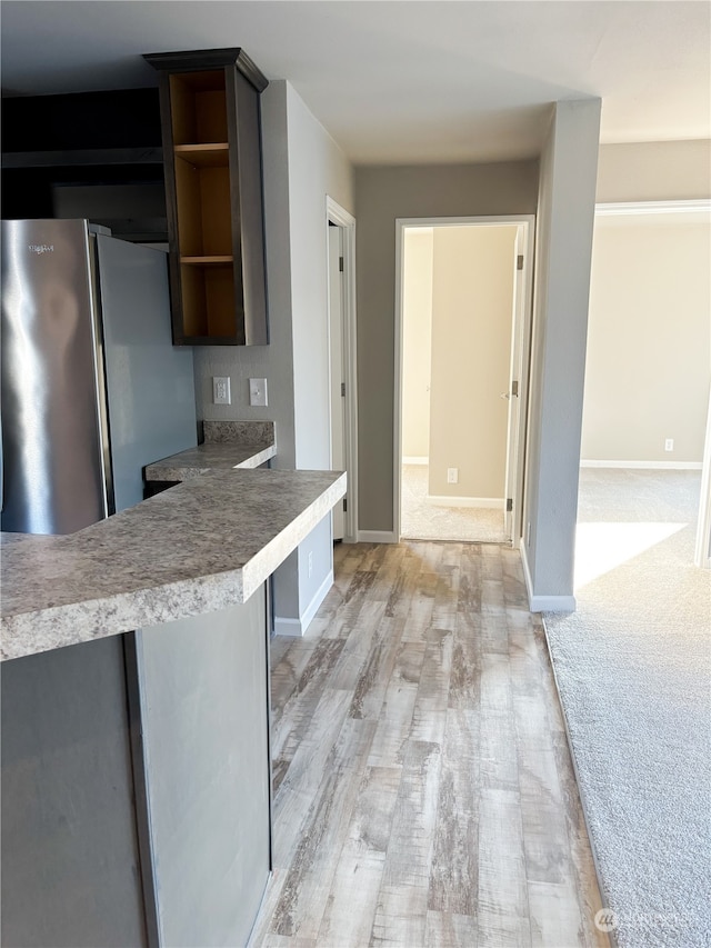 kitchen with kitchen peninsula, stainless steel fridge, and light carpet