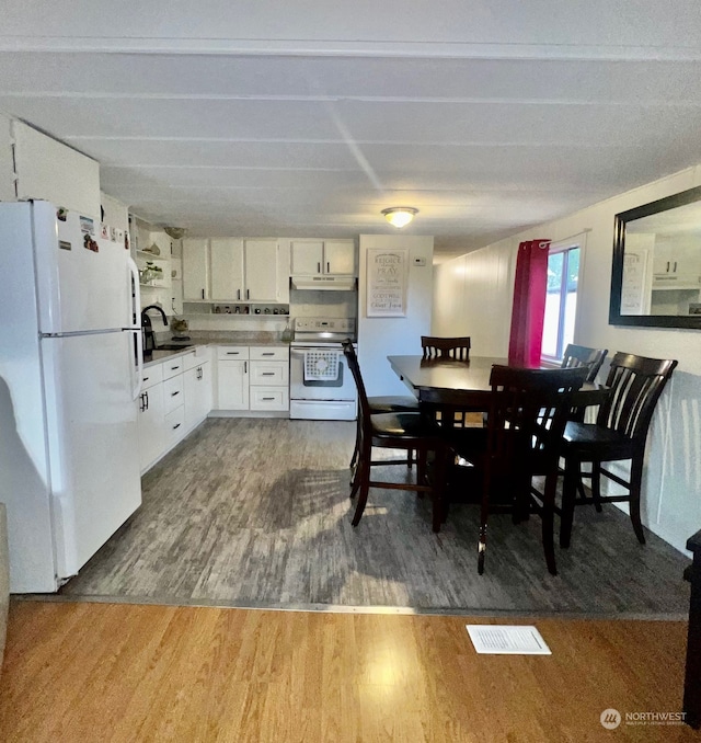 kitchen with hardwood / wood-style flooring, sink, white appliances, and white cabinets