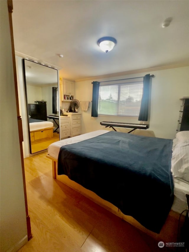 bedroom with light hardwood / wood-style floors and ornamental molding