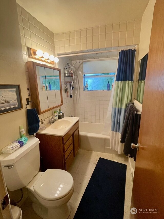 full bathroom featuring tile walls, toilet, tile patterned floors, shower / bath combination with curtain, and vanity