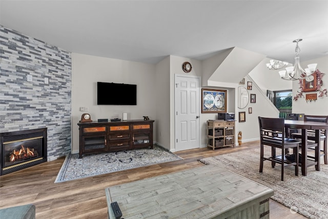 living room featuring a notable chandelier, wood-type flooring, and a tile fireplace