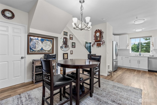 dining space with sink, light hardwood / wood-style flooring, and an inviting chandelier