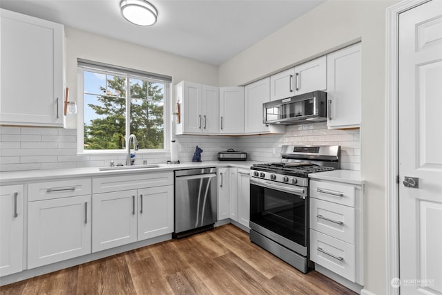 kitchen with hardwood / wood-style flooring, stainless steel appliances, sink, and white cabinets