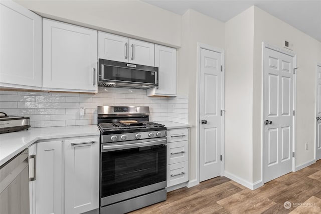 kitchen with backsplash, light hardwood / wood-style flooring, white cabinetry, and gas stove