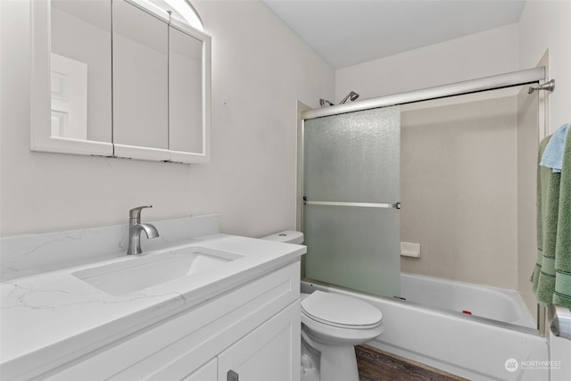 full bathroom featuring wood-type flooring, vanity, shower / bath combination with glass door, and toilet