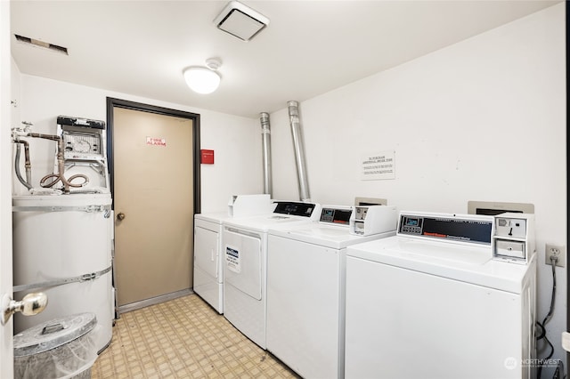 clothes washing area with light tile patterned flooring, independent washer and dryer, and secured water heater