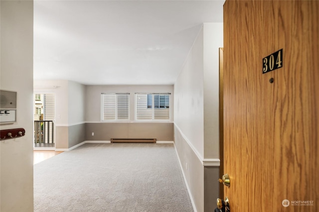 interior space with baseboards, baseboard heating, and carpet flooring